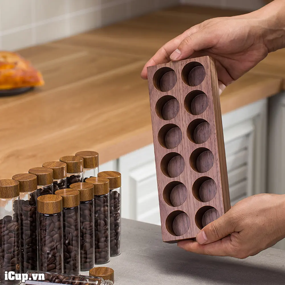 Trên tay khay gỗ óc chó đựng 12 ống thủy tinh chứa cà phê Trên tay khay gỗ óc chó đựng 12 ống thủy tinh chứa cà phê